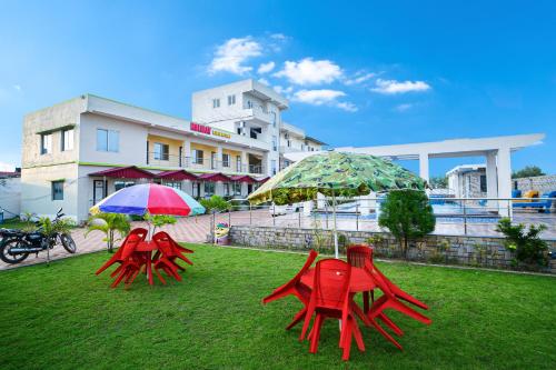 two red chairs and umbrellas sitting on a lawn at Holiday Beach Resort !! Beach Distance 50 Mts !! in Mandarmoni