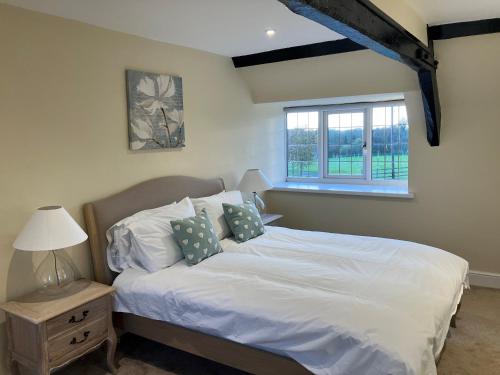 a bedroom with a white bed with a window at Aynho Cottages in Banbury