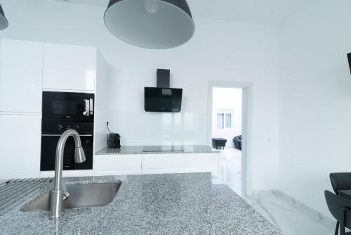 eine weiße Küche mit einer Spüle und einer Theke in der Unterkunft Isle Home By CanariasGetaway in Guanarteme