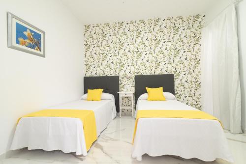 zwei Betten in einem Zimmer mit weißen Wänden und gelben Kissen in der Unterkunft Isle Home By CanariasGetaway in Guanarteme