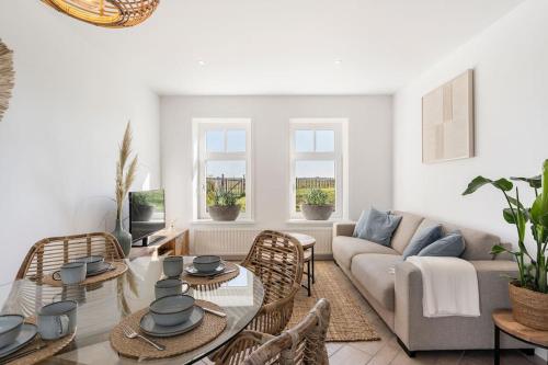 a living room with a couch and a table and chairs at Coastal Cottages huisje Bries in Ouddorp