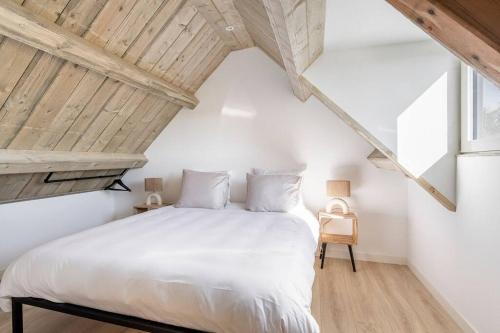 a bedroom with a white bed in a attic at Huisje Bries, Nieuw! mooi uitzicht, vlakbij strand in Ouddorp