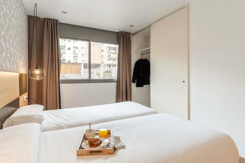 two beds in a hotel room with a tray of food at AB Sagrada Familia Premium in Barcelona