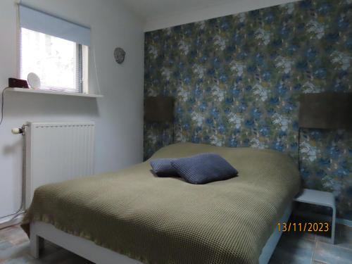 a bedroom with a bed with a blue pillow on it at Vakantiehuis Onder de Peppel met sauna en jacuzzi in Wijk en Aalburg