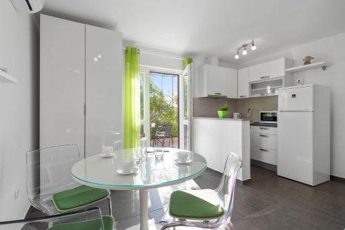 uma cozinha com uma mesa de vidro e cadeiras verdes em Studio Apartment Sekula em Sibenik