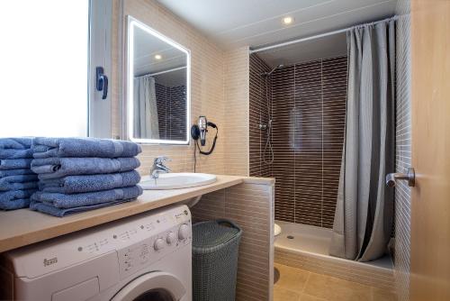 uma casa de banho com uma máquina de lavar roupa e um lavatório em NIDO 380G em Roses