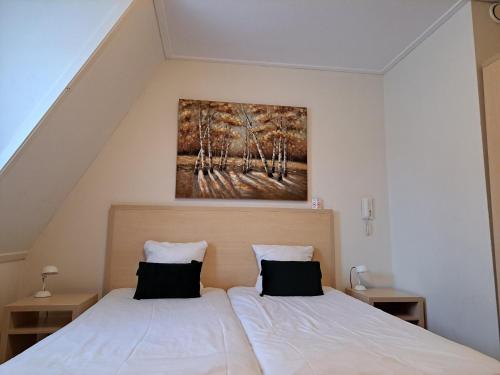 a bedroom with two beds and a painting on the wall at Hotel Restaurant Boven Groningen in Delfzijl