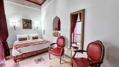 a bedroom with a bed and two red chairs at Riad Argan in Marrakesh