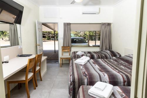 ein Hotelzimmer mit 2 Betten und einem Schreibtisch in der Unterkunft Benaraby Hilltop MotorInn in Benaraby