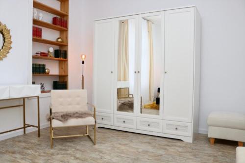 a white dressing room with a chair and a mirror at Herman Apartment Cisnadie in Cisnădie
