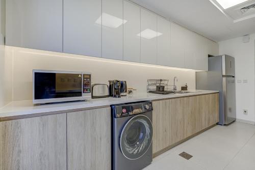 a kitchen with a washing machine and a microwave at #54 High End 2BR in Mirdif hills in Dubai