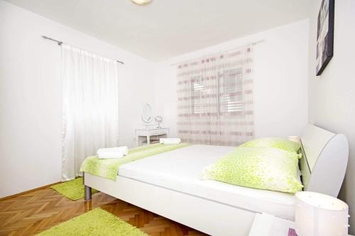 a white bed in a room with a window at Apartman Makarska in Makarska