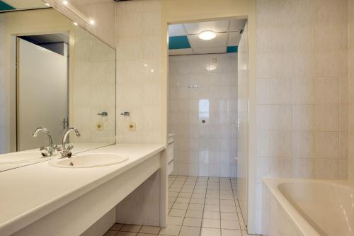 een badkamer met een wastafel, een bad en een spiegel bij Appartement Strand Makkum in Makkum