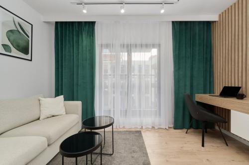 a living room with green curtains and a couch at Cosy Studio with access to Gym and Spa Area by Renters in Wrocław