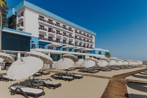 a row of beach chairs and umbrellas in front of a hotel at Arkin Palm Beach Hotel in Mağusa