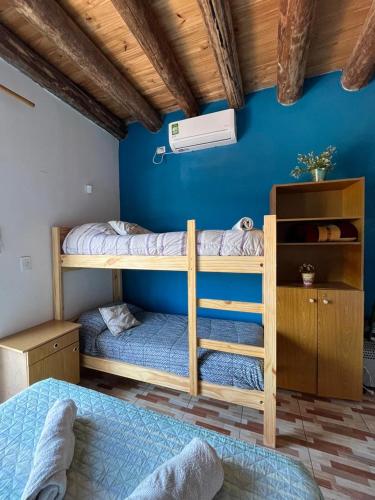 two bunk beds in a room with a blue wall at Monoambiente lo de Carola Mendoza in Las Heras