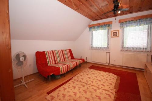 a living room with a red couch and a fan at Green Oasis in Mozirje