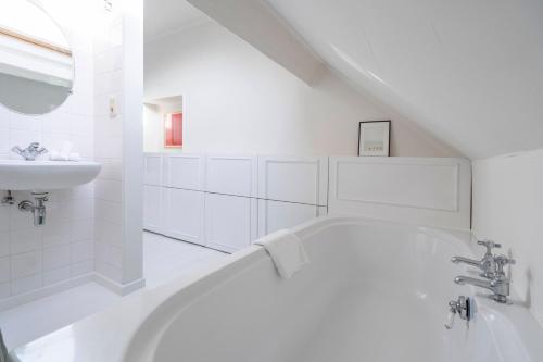 La salle de bains blanche est pourvue d'une baignoire et d'un lavabo. dans l'établissement The Handshake House, à Anvers