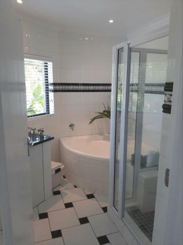 a white bathroom with a tub and a sink at Studio @ 32 in Ballito