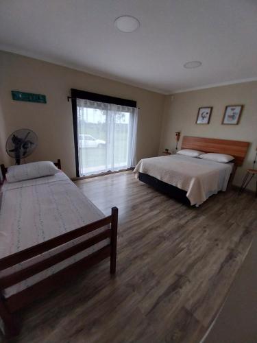 a bedroom with two beds and a wooden floor at Guidai Alojamiento in Tacuarembó