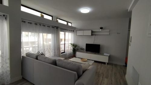 ein Wohnzimmer mit einem Sofa und einem TV in der Unterkunft Apartamento El Puerto del Médano in El Médano