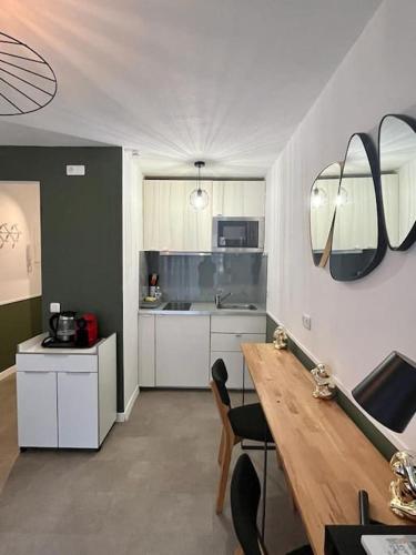 une cuisine avec des armoires blanches et une table en bois dans l'établissement Studio de charme coeur de ville!, à Sète