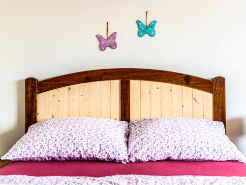 a bed with a wooden headboard with butterflies on the wall at Levandulová chalupa in Vrbice