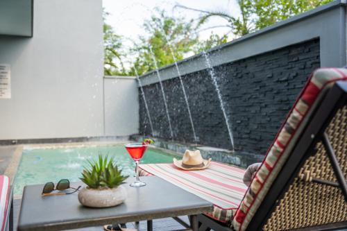 a patio with a table with a drink and a hat at Indaba Lodge Gaborone in Gaborone