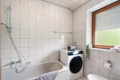 a bathroom with a tub and a washing machine at Apartment Bodman in Friedrichshafen in Friedrichshafen