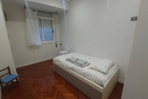 a bedroom with a bed and a chair and a window at Piso lujo en Gran Vía con garaje in Vigo