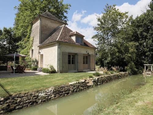 an old house with a stone wall next to a river at Le Pigeonnier Colbert in Rouvray