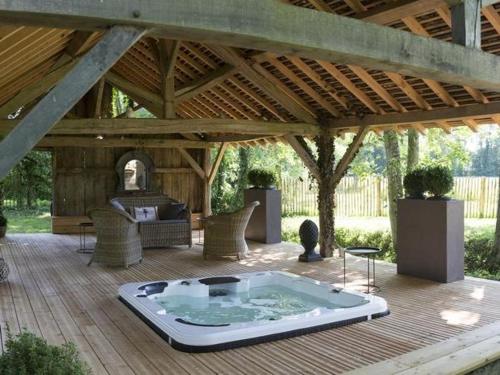 a hot tub on a wooden deck with a pavilion at Le Pigeonnier Colbert in Rouvray