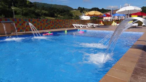 a pool with two water fountains in a swimming pool at Conjunto Hotelero La Pasera in Soto de Cangas