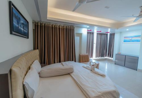 un dormitorio con una gran cama blanca con un animal de peluche. en Urmee Guest House, en Cox's Bazar
