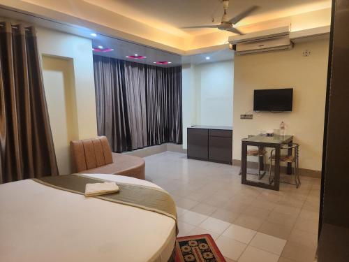 um quarto de hotel com uma cama e uma televisão em Urmee Guest House em Cox's Bazar