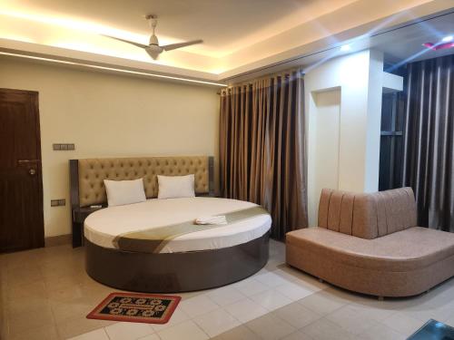 una camera con un grande letto e una sedia di Urmee Guest House a Cox's Bazar