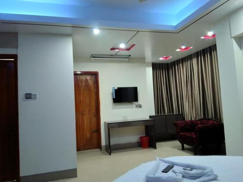 Habitación con cama, TV y sofá. en Urmee Guest House, en Cox's Bazar