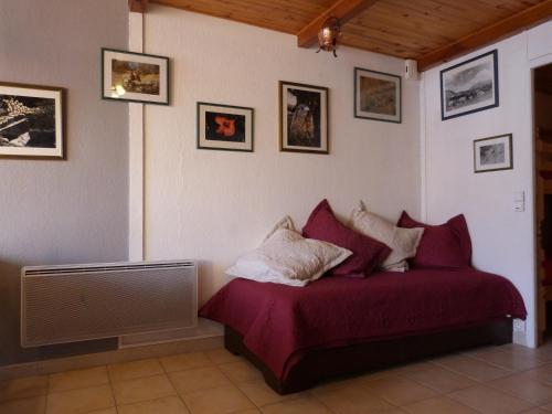 uma cama vermelha num quarto com fotografias na parede em T2 CBU Le Sauze em Enchastrayes