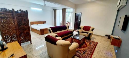 a living room with a couch and chairs and a bed at Hosamane Farm Inn in Sringeri