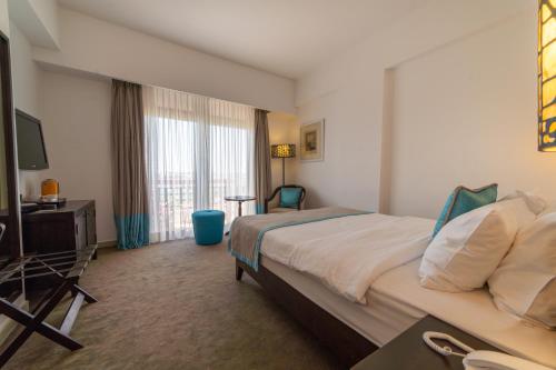 a hotel room with a large bed and a television at Arkin Palm Beach Hotel in Mağusa