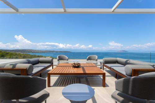 a patio with couches and a table with a view at Villa Artemis - New Magnificent Beachfront Villa with Infinity Pool! in Kranidi