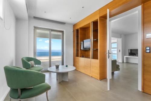 a living room with a green chair and a table at Villa Artemis - New Magnificent Beachfront Villa with Infinity Pool! in Kranidi