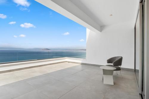 a white room with a chair and a large window at Villa Artemis - New Magnificent Beachfront Villa with Infinity Pool! in Kranidi