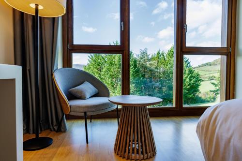 a room with a chair and a table and a window at Hotel & Spa El Mirador de Ulzama in Urrizola-Galáin