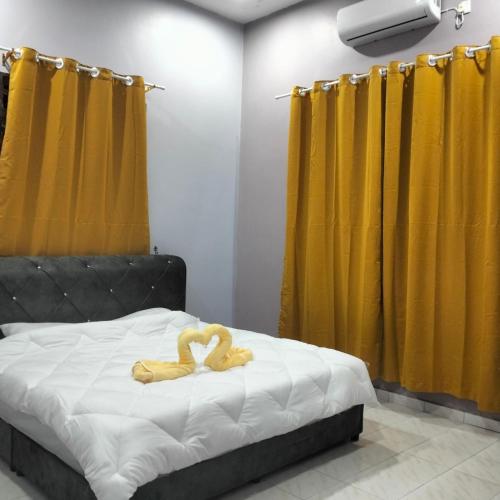 1 dormitorio con 1 cama con cortinas amarillas en Rezqrich Villa Homestay 2, en Kampung Degong