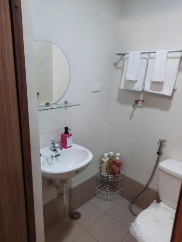 uma casa de banho com um lavatório, um espelho e um WC. em Malachai's Place Spring Residences em Manila