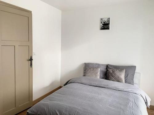 a bedroom with a bed and a white wall at L'Ulmeusienne contemporaine in Le Meux