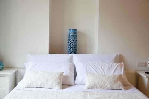 a white bed with white pillows and a blue vase at Mela & Cannella accommodation in Minori