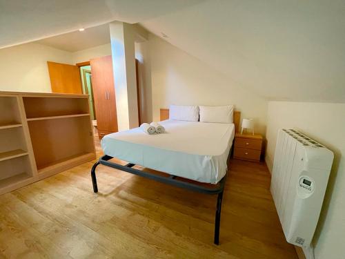 a bedroom with a white bed and a refrigerator at Apartamentos Pantebre 3000 in Pas de la Casa