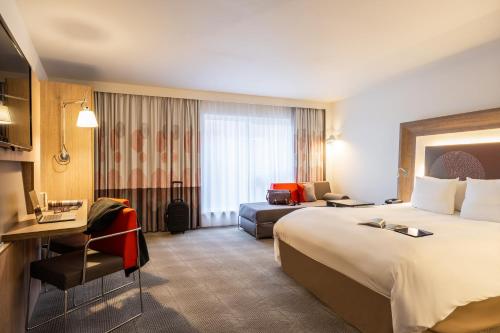 Novotel Mechelen Centrum في ميشيلين: غرفة فندقية بسرير كبير واريكة